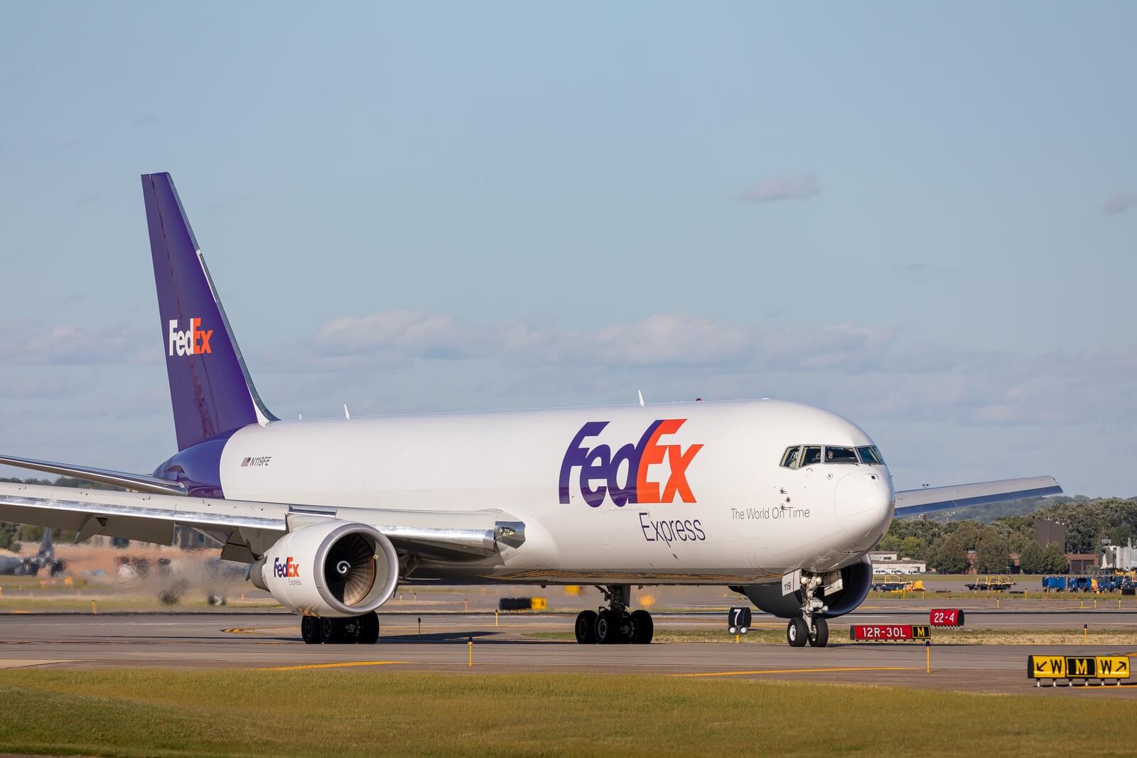 Fedex white, orange and purplepassenger plane on airport during daytime