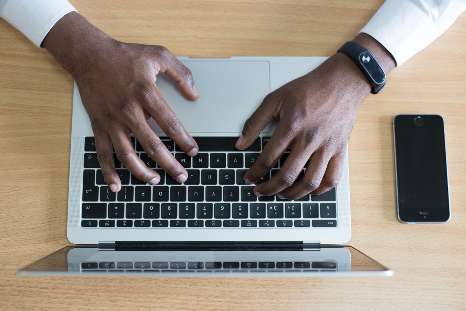 person's hand typing application letter on MacBook near iPhone flat lay photography